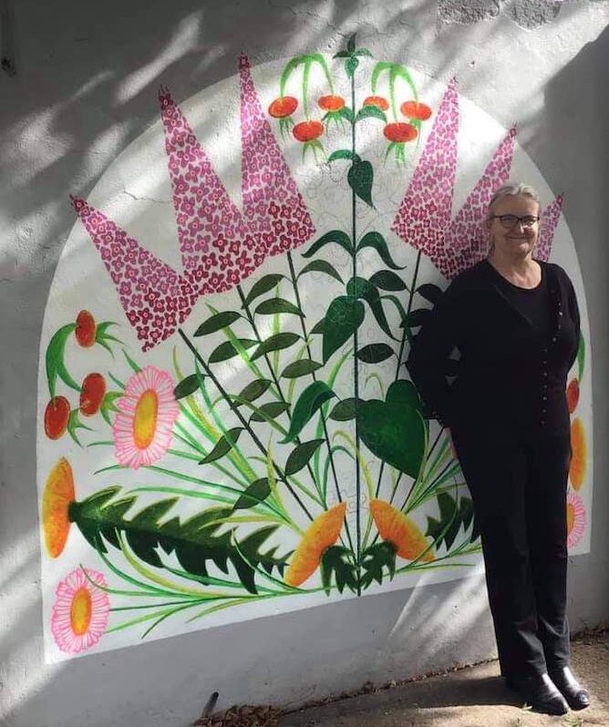 Resident artist Irena stands in front of her floral mural